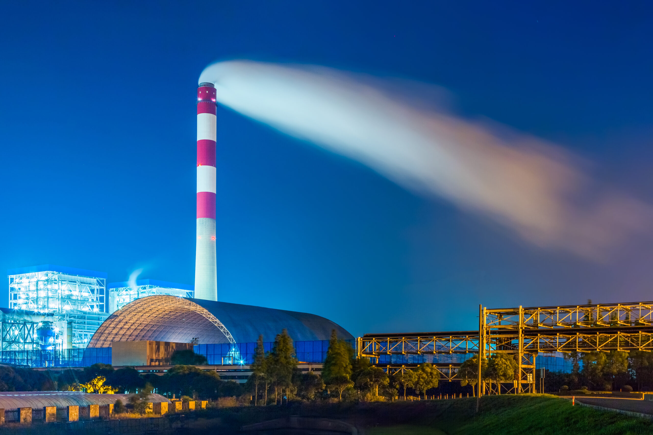 factory with smoke stack against sky at night