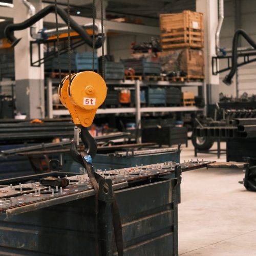 Close-up of a yellow industrial crane hook in a manufacturing workshop in Konya, Türkiye, showcasing metalwork.